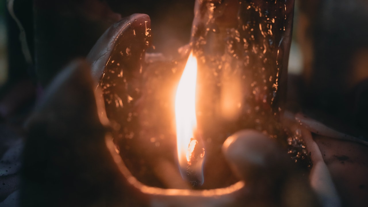 Bougie allumée avec de la cire fondue, flamme et reflets chauds