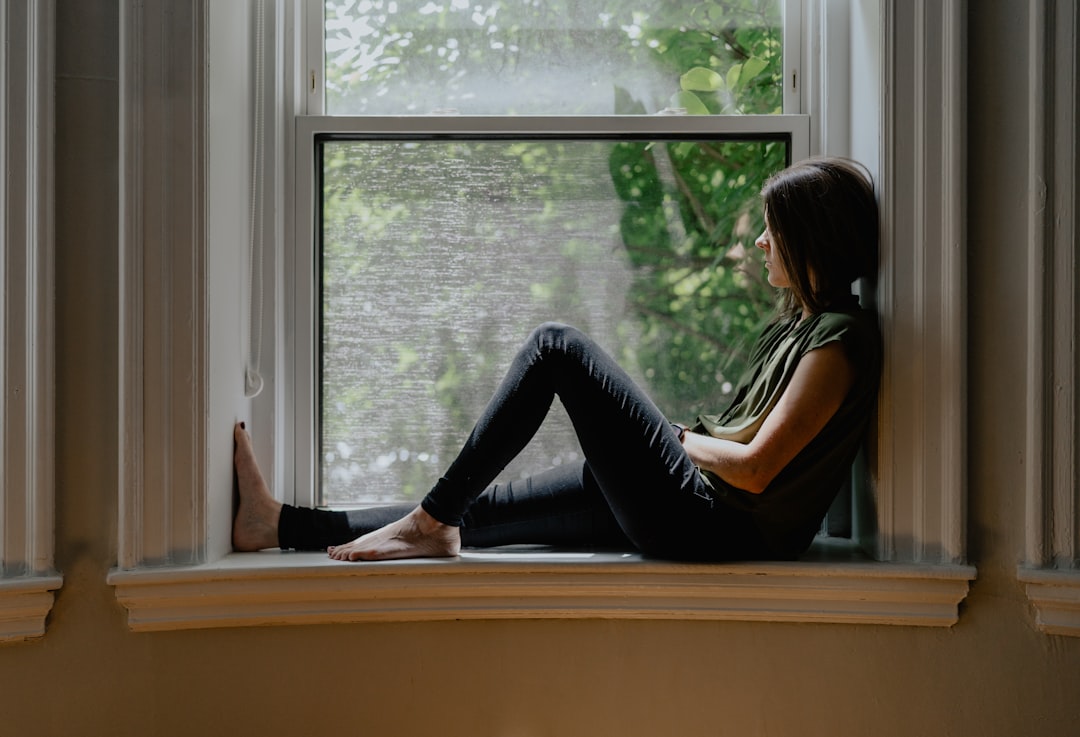 Femme pensive à la fenêtre se demandant que fait le PN dans son dos