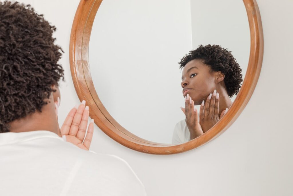 Adolescent garçon appliquant un soin sur son visage pour le traitement de l'acné